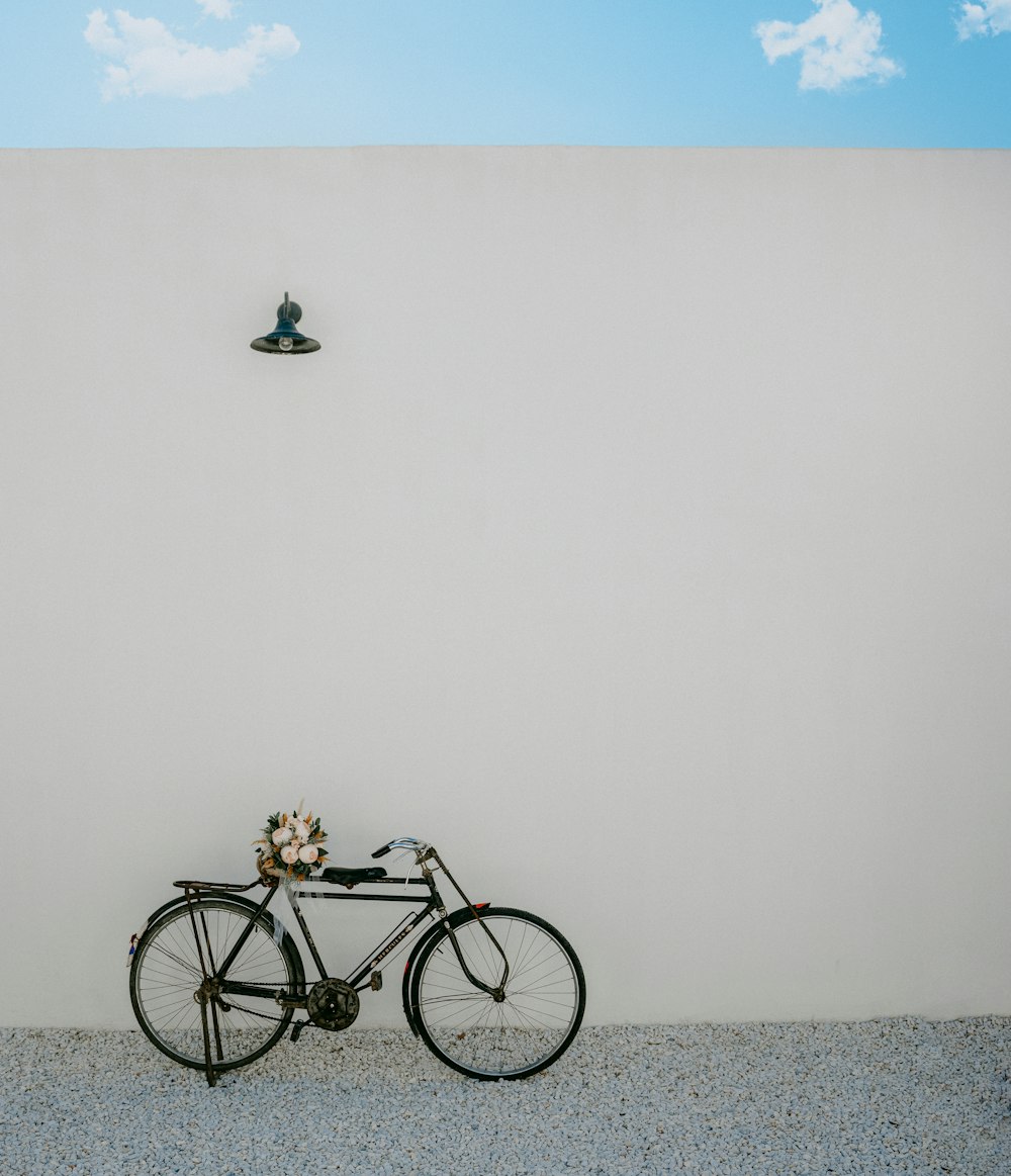 a bicycle parked in front of a wall with a boat in the background