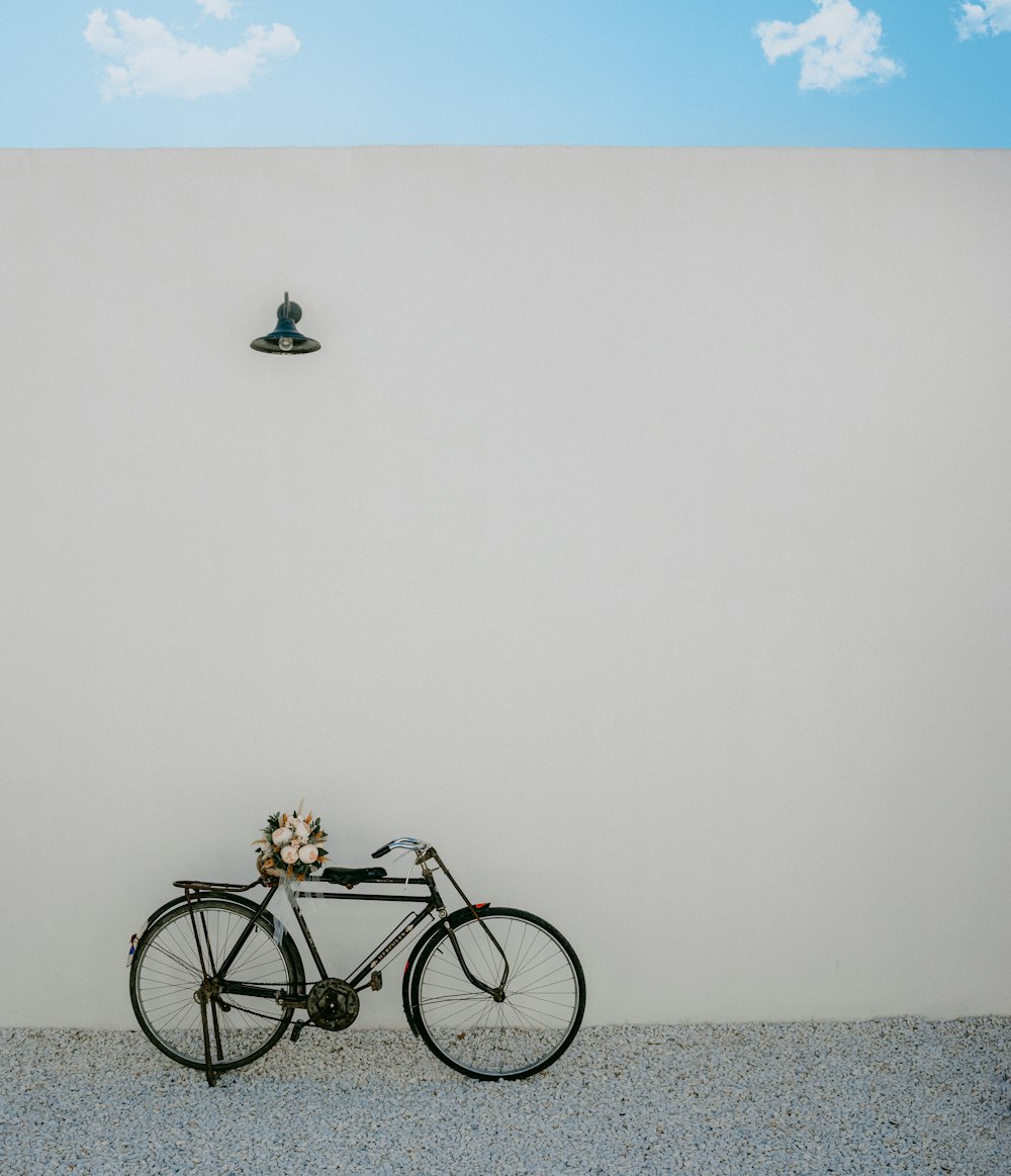 Una bicicleta estacionada frente a una pared con un bote al fondo