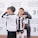 A group of children wearing black and white soccer uniforms are standing on a sports field. One child is smiling broadly, while another makes a playful gesture. They are near a backdrop with the Shanghai American School and Juventus Academy logos.