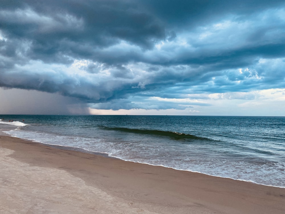 a beach with waves and clouds