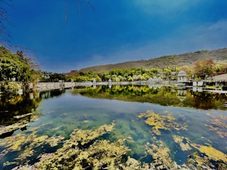 A serene artificial lake surrounded by lush greenery and smooth stone edges, reflecting the clear sky.