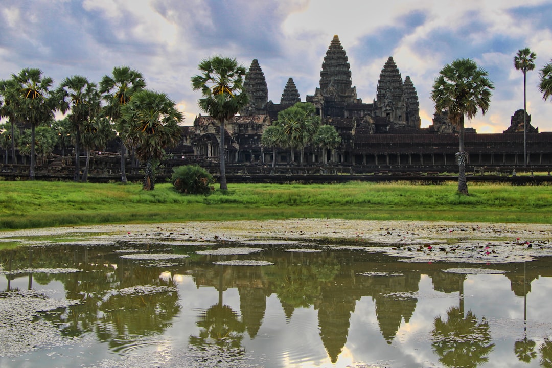 a body of water with trees and buildings in the background with Angkor Wat in the background, The reflection of Angkor W