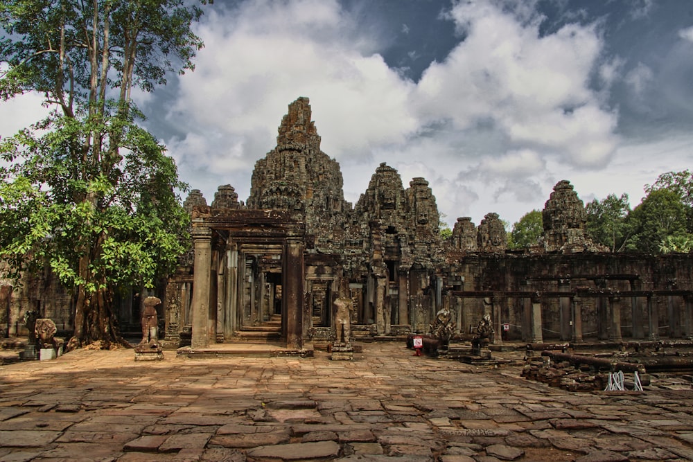 a stone building with pillars and statues with Angkor Wat in the background