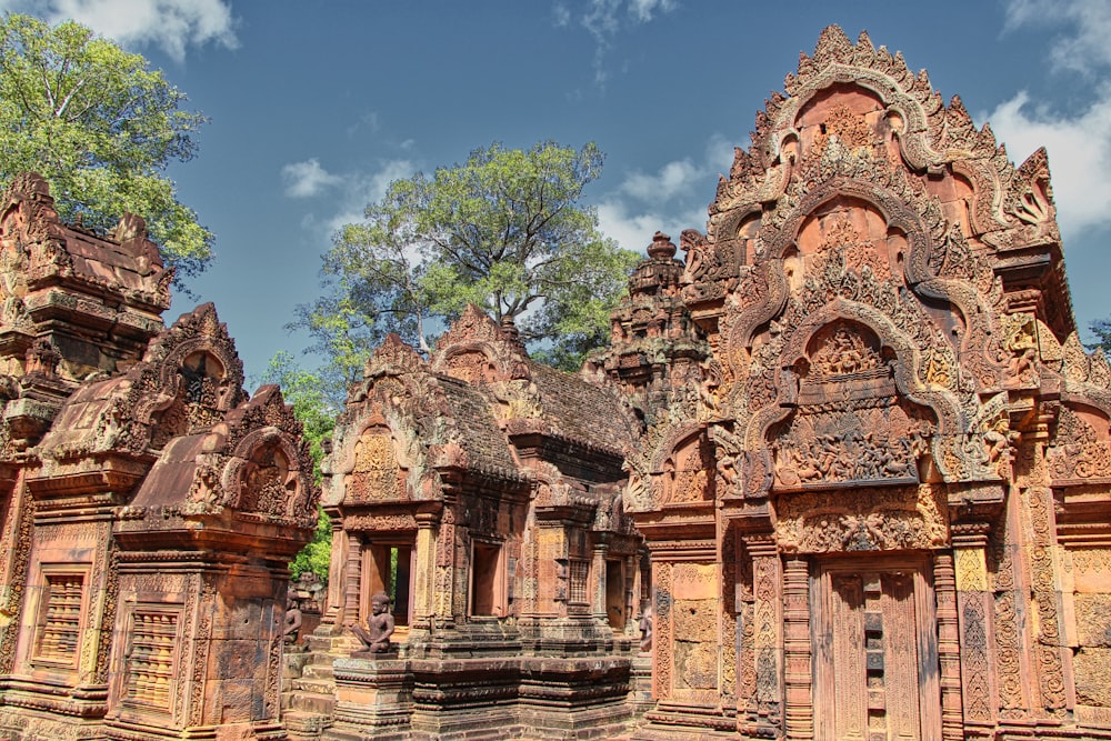 a large stone building with trees with Banteay Srei in the background