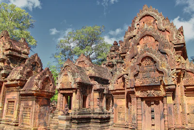 Ornately carved pink sandstone central sanctuary towers at Banteay Srei (via Unsplash)