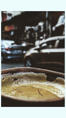 Close-up of a steaming cup of spiced chai with traditional North Karnataka pottery in the background.