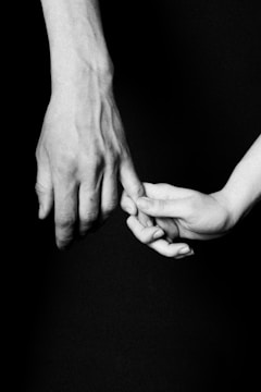 A close-up of intertwined hands, one human, one clawed.