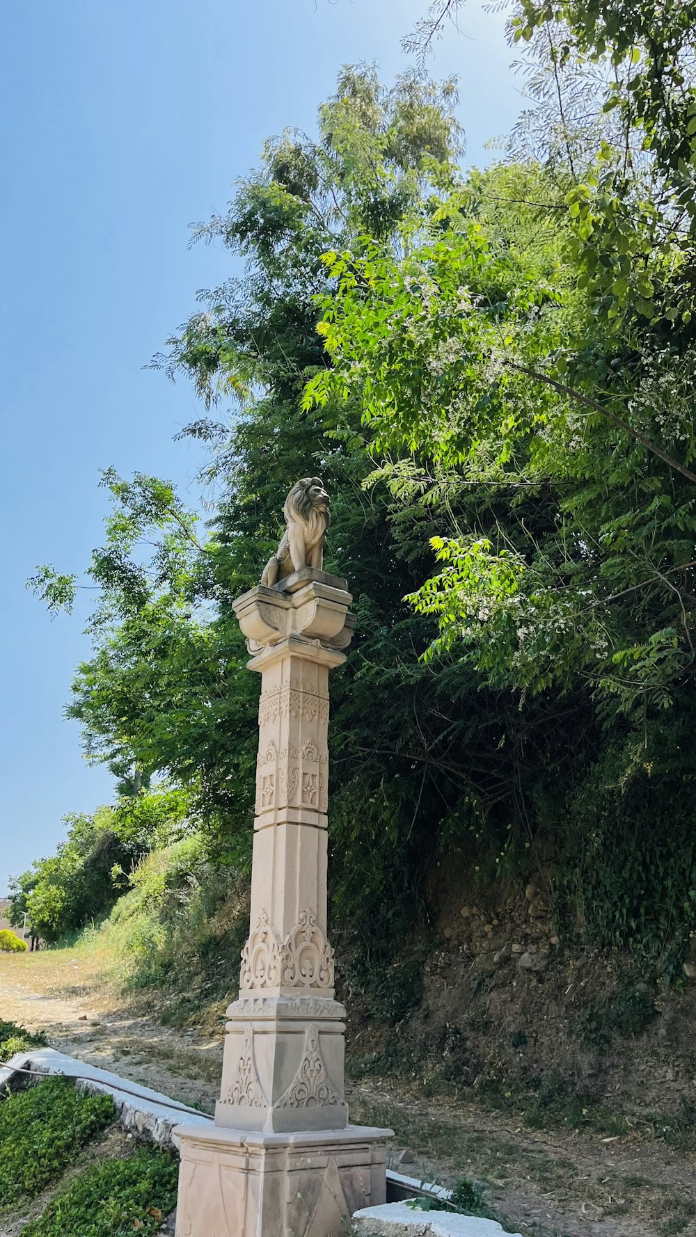 a statue of a person on a stone pillar in front of trees