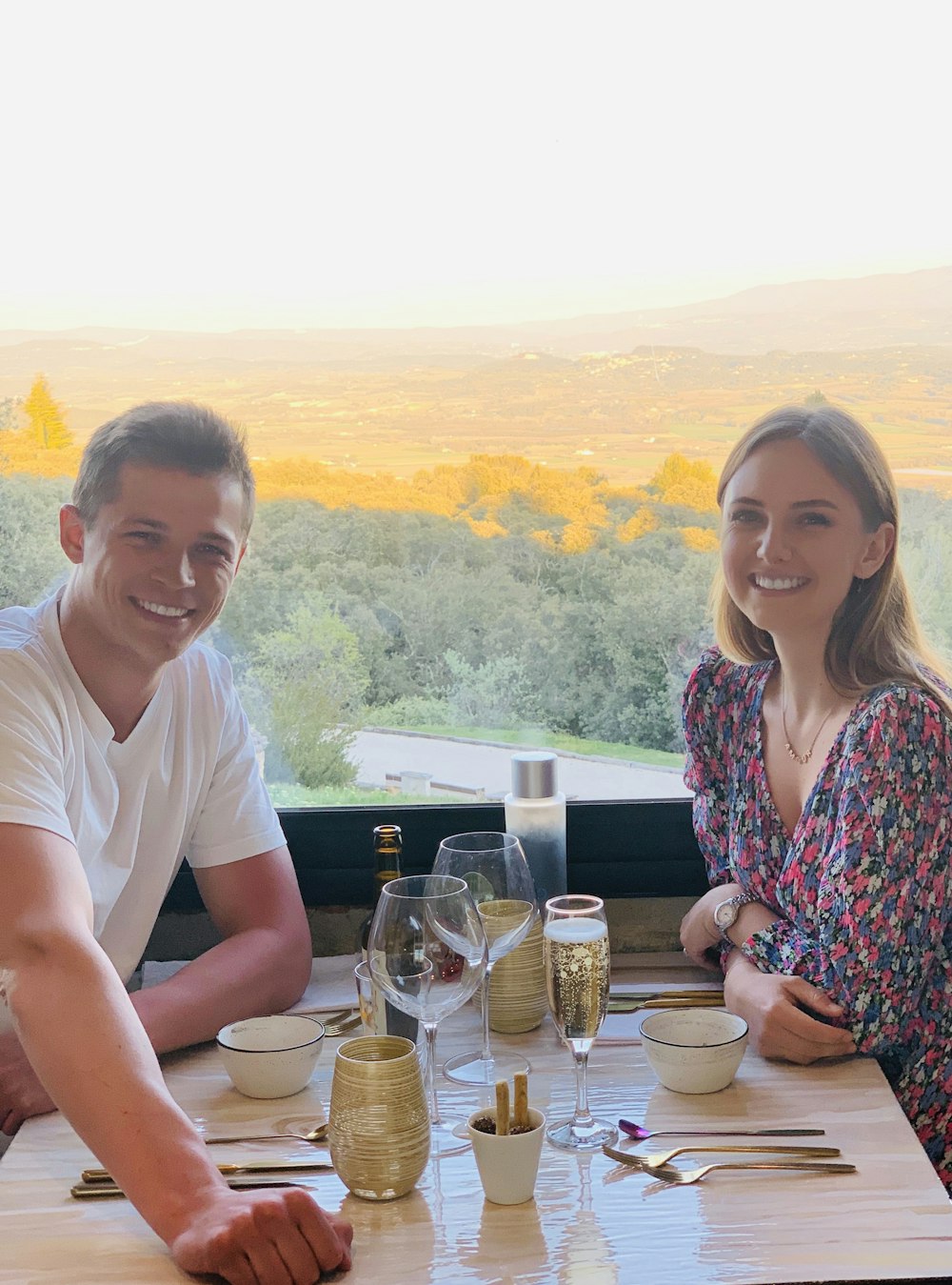 a man and woman sitting at a table with drinks and food