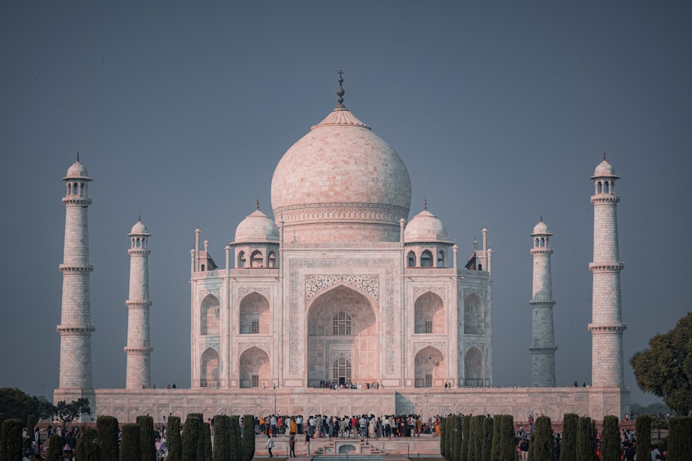 ein großes weißes Gebäude mit einer Kuppel und Türmen mit Taj Mahal im Hintergrund