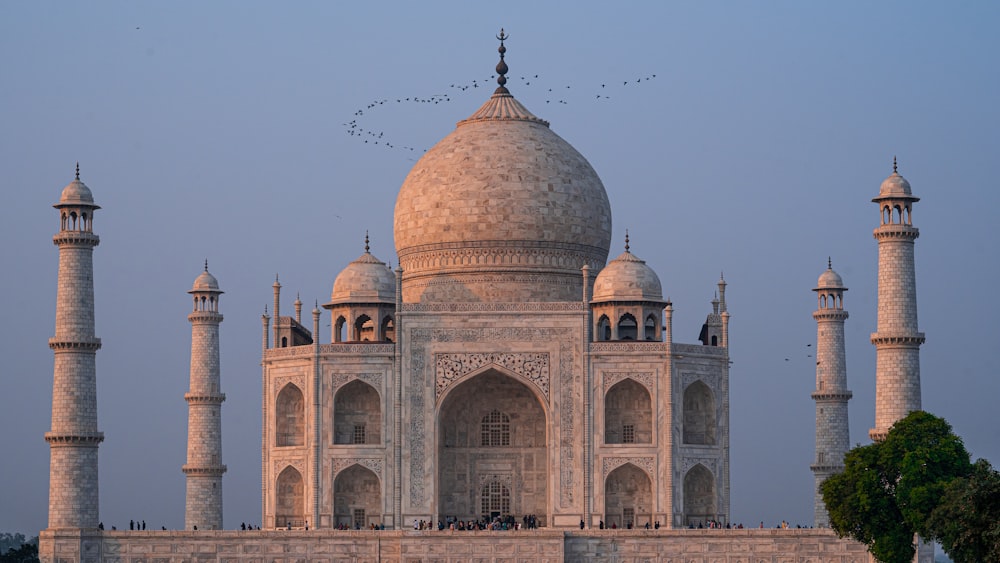 ein großes Gebäude mit Türmen mit Taj Mahal im Hintergrund