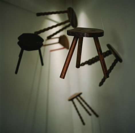 A collection of handcrafted wooden stools arranged artistically on a polished concrete floor.