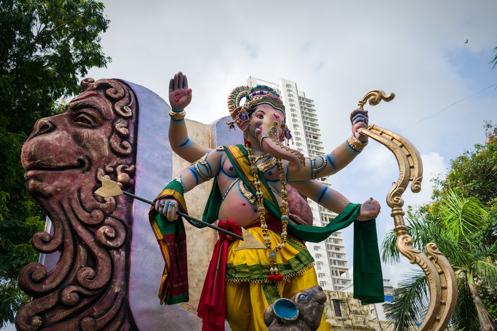 a person in a garment holding a staff and a statue