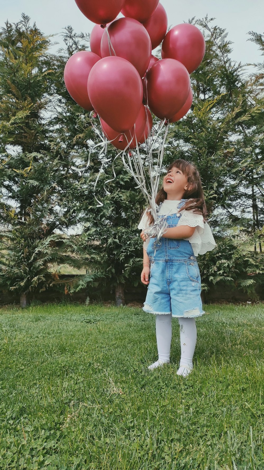 a girl holding a bunch of balloons