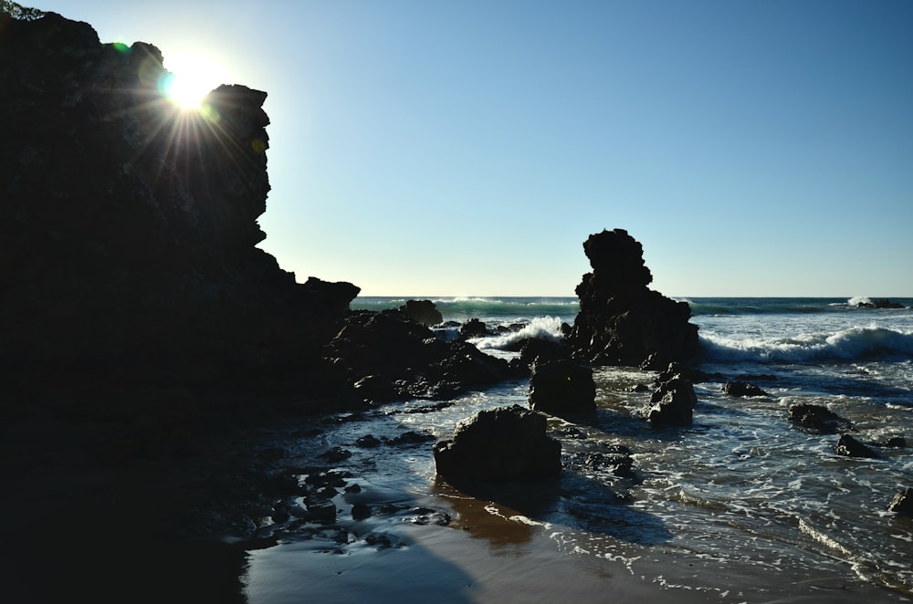 Una playa rocosa con el sol brillando