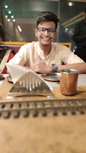 A smiling dark-haired waiter warmly welcoming tourists at a cozy restaurant.