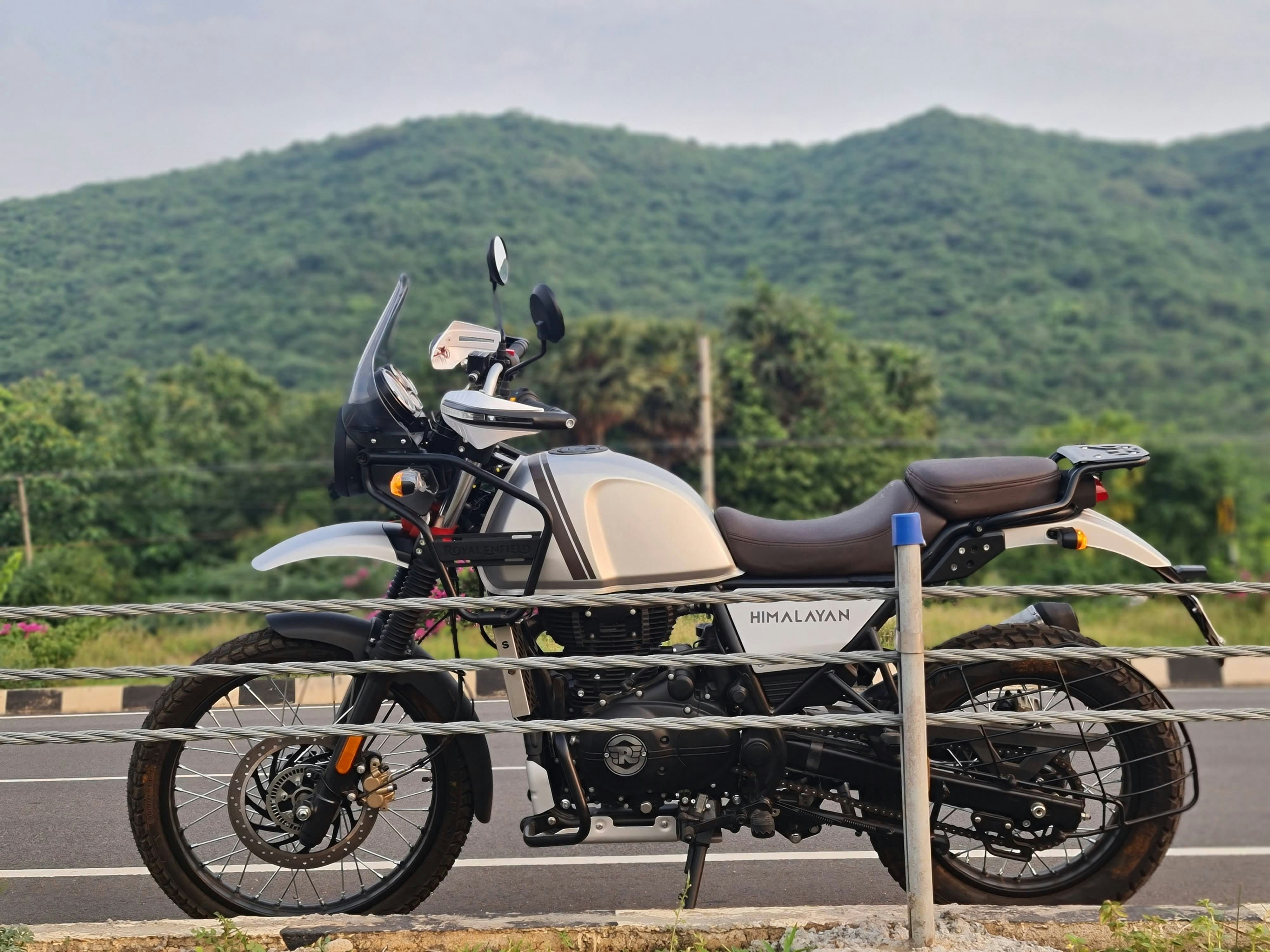 Royal Enfield Himalayan motorcycle parked on mountain road with scenic backdrop