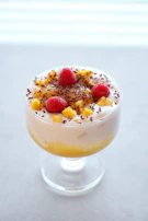 An elegant glass of mango lassi with a sprinkle of cardamom on top.