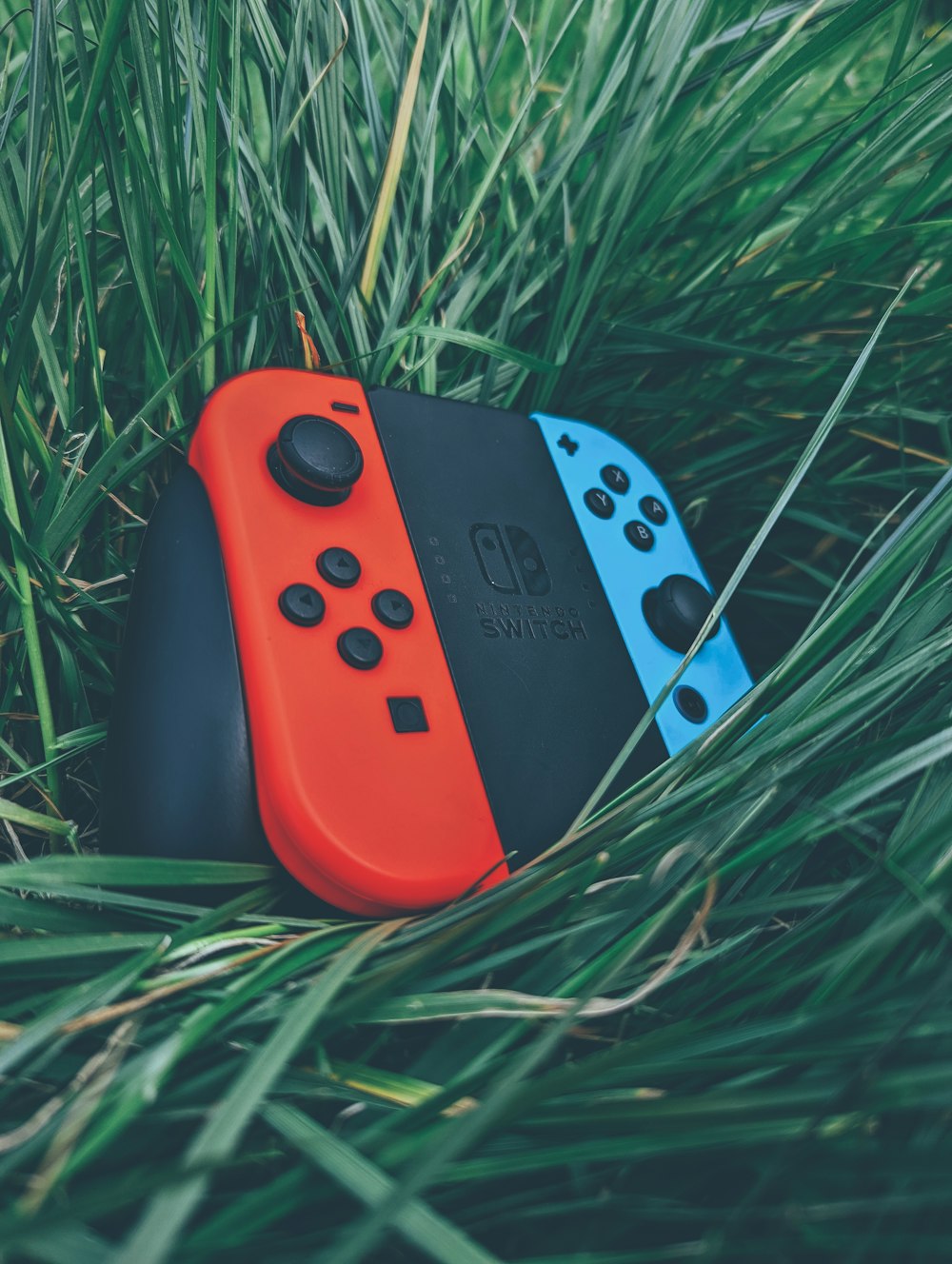 a red and black video game controller on grass