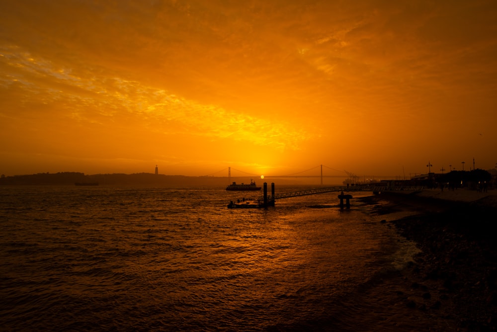 a body of water with boats in it and a sunset in the background