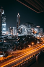 a city with a large globe and buildings at night