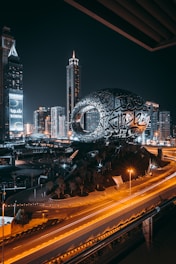 a city with a large globe and buildings at night