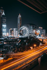 a city with a large globe and buildings at night