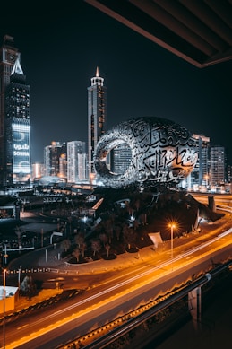 a city with a large globe and buildings at night