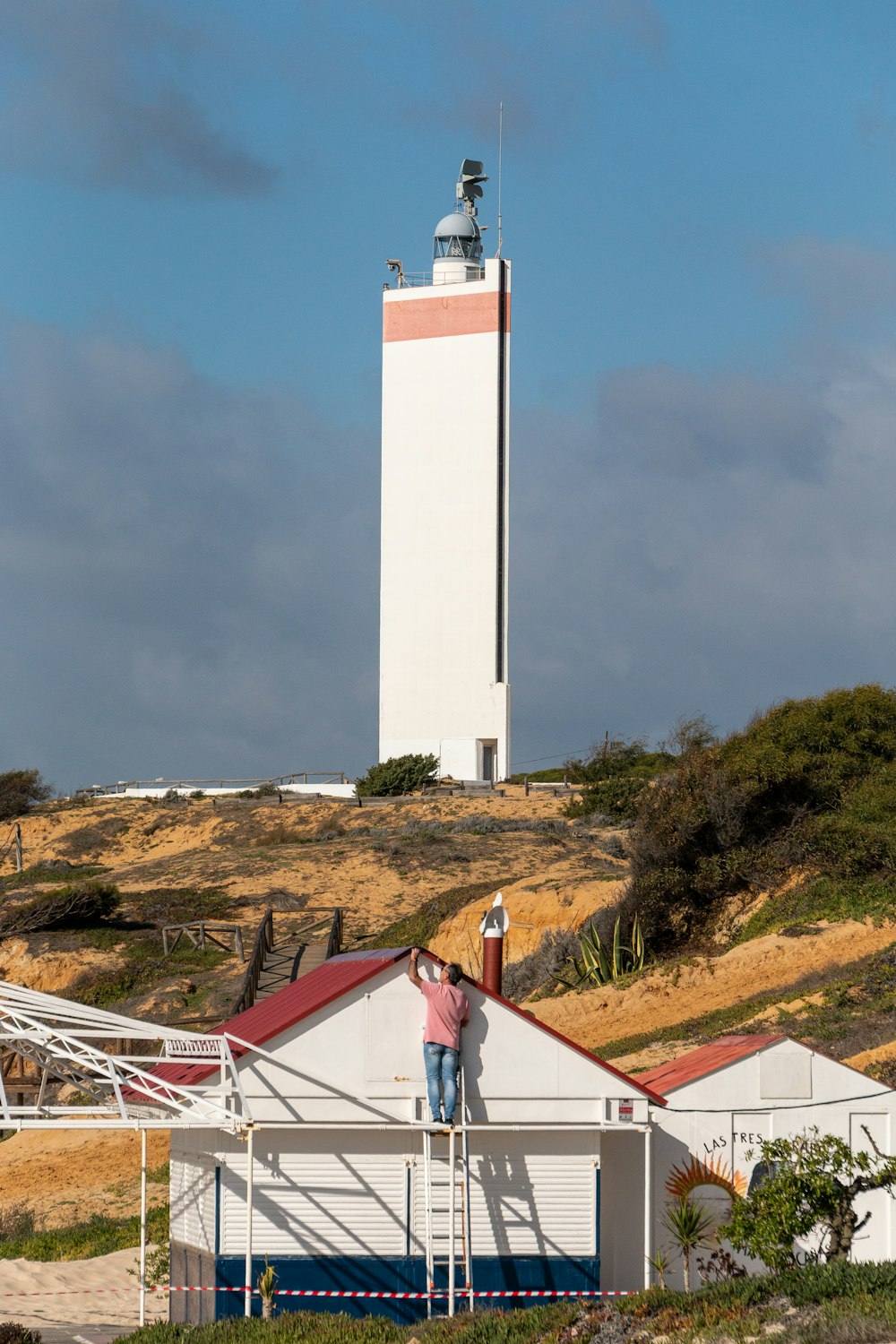 灯台を背景に白いテントの上に立っている人