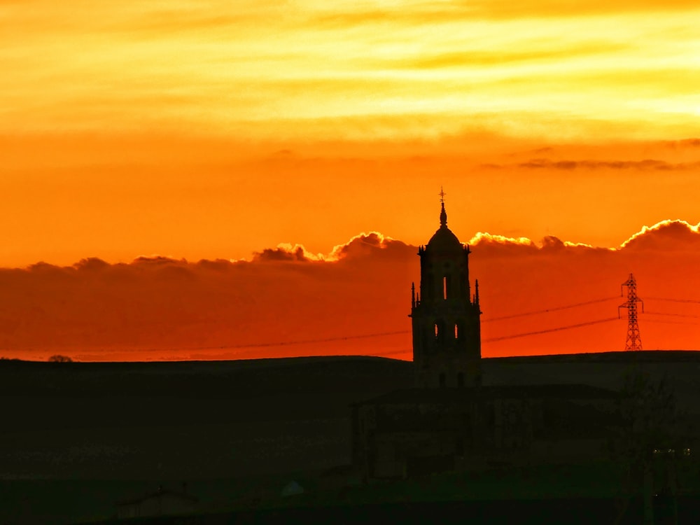 a building with a tower and a sunset in the background