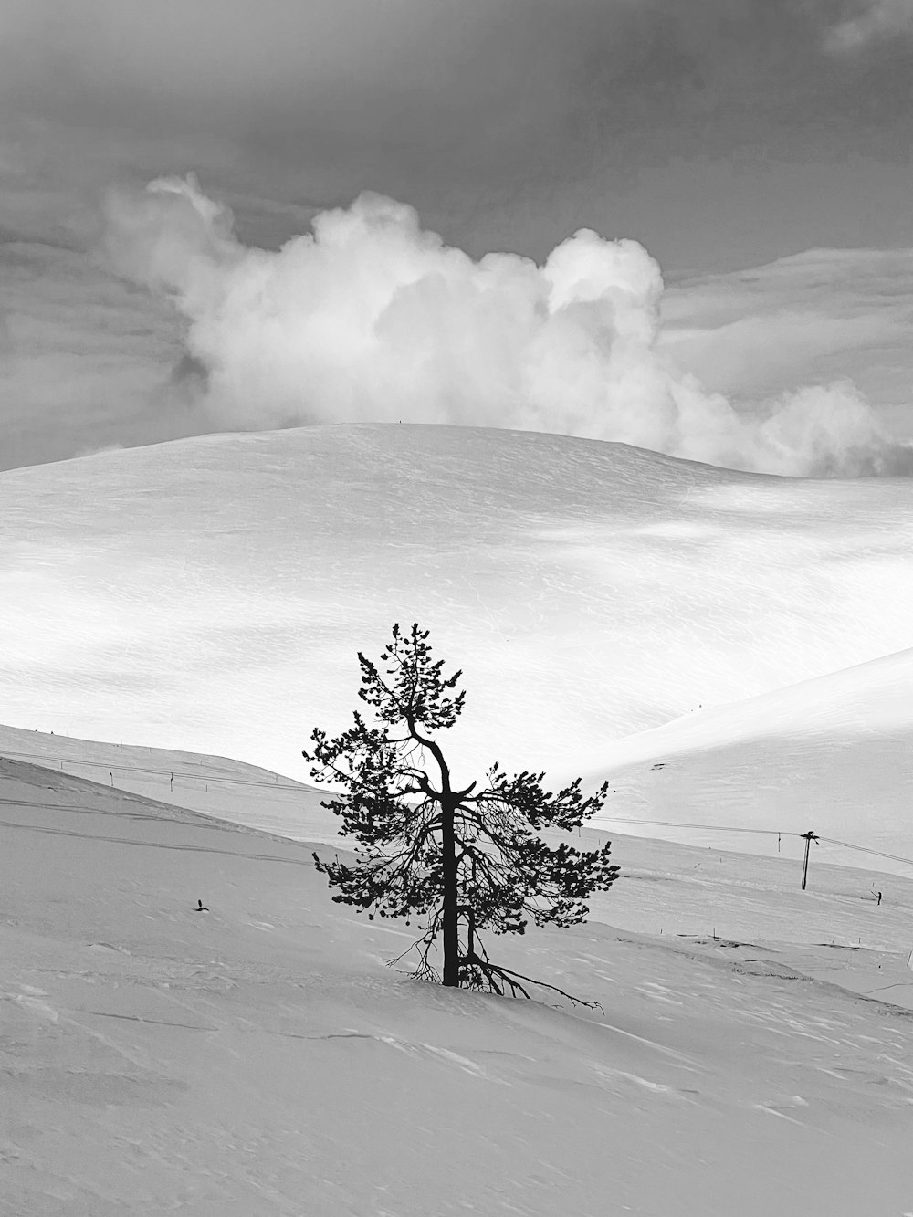 a group of clouds in the sky over a snow covered slope