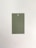 A rectangular paper card with a hole at the top center placed on a neutral, light background. The card is a muted green color.