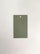 A rectangular paper card with a hole at the top center placed on a neutral, light background. The card is a muted green color.