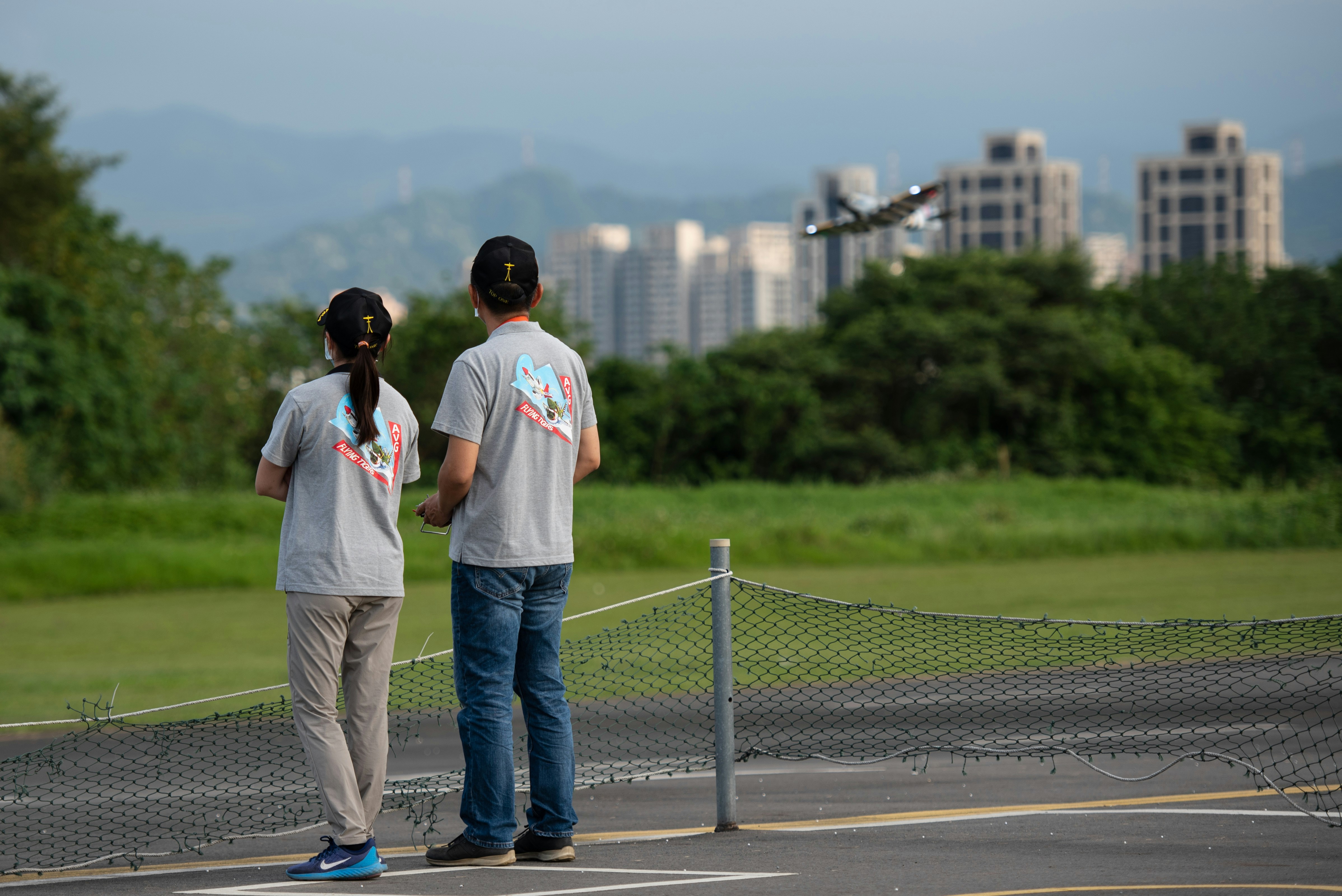 a couple of people standing on a road with a city in the background