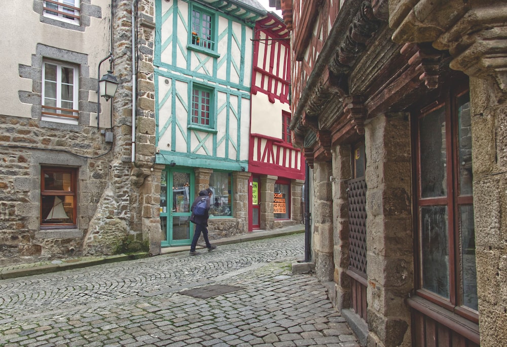 a person walking on a cobblestone street between buildings