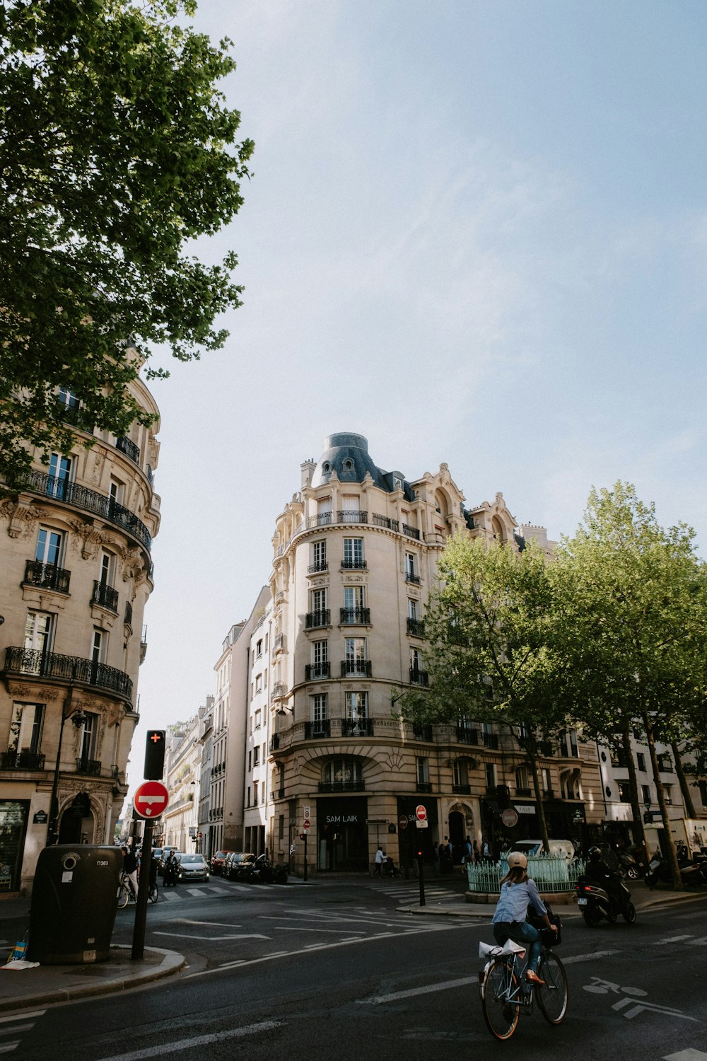 a person riding a bicycle on a street with trees and buildings