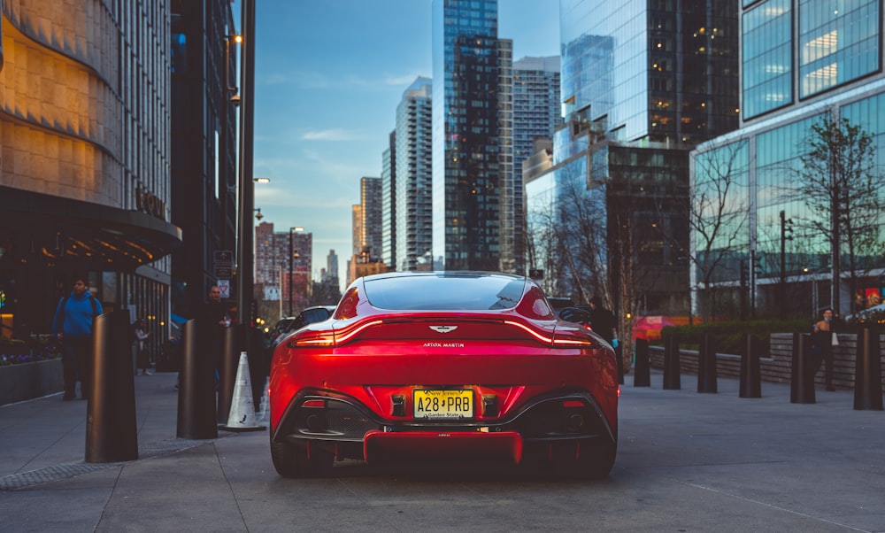 a red sports car parked on a street with tall buildings in the background