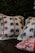 Four pillows featuring embroidered floral patterns are placed together. Two of the pillows have intricate designs with blue and red flowers, while one has a red and white striped pattern. The background is dark, making the pillows stand out.