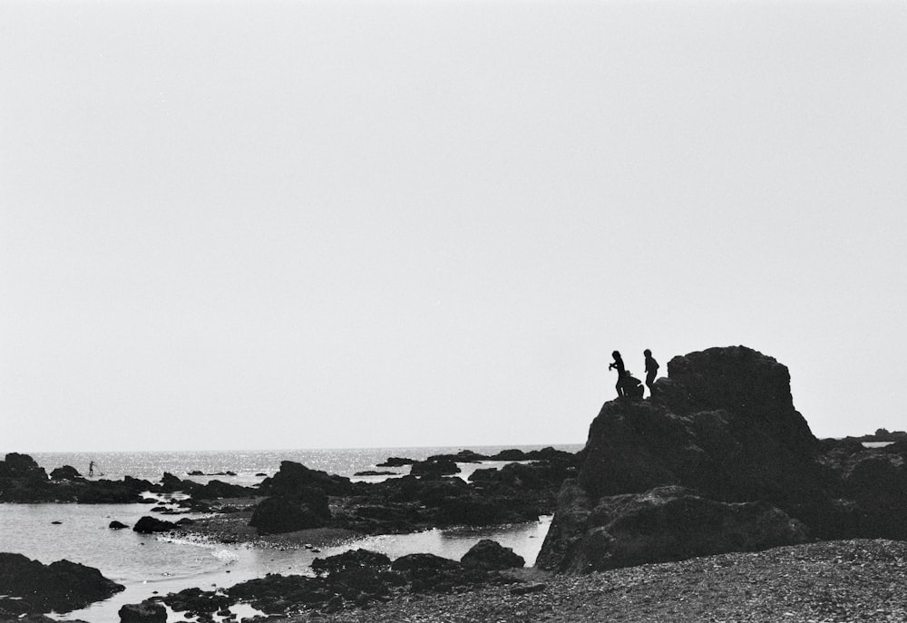 a group of people standing on a rock in the water