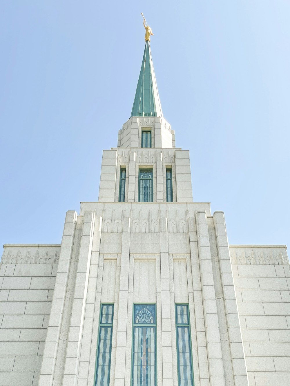 a white building with a green steeple and a gold cross on top