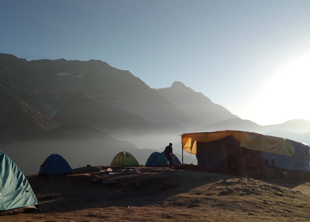 a person standing next to a group of tents in a snowy place