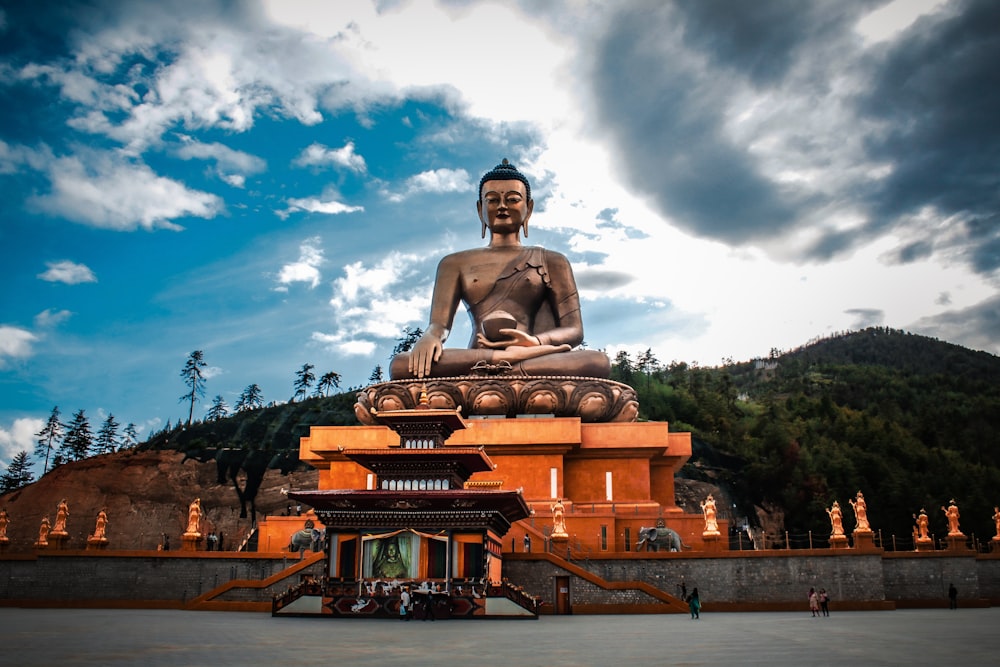 a statue of a man sitting on a throne in front of a building