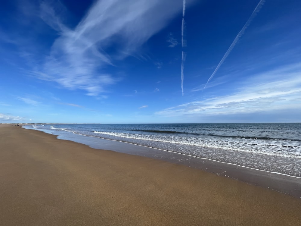 a sandy beach with waves and blue sky