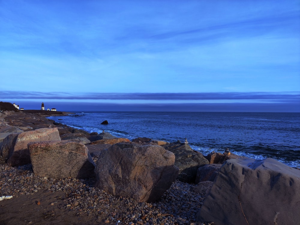 a rocky beach with a body of water in the background