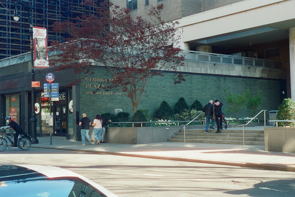 a group of people standing on the sidewalk in front of a building