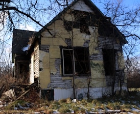 a run down house with trees around it