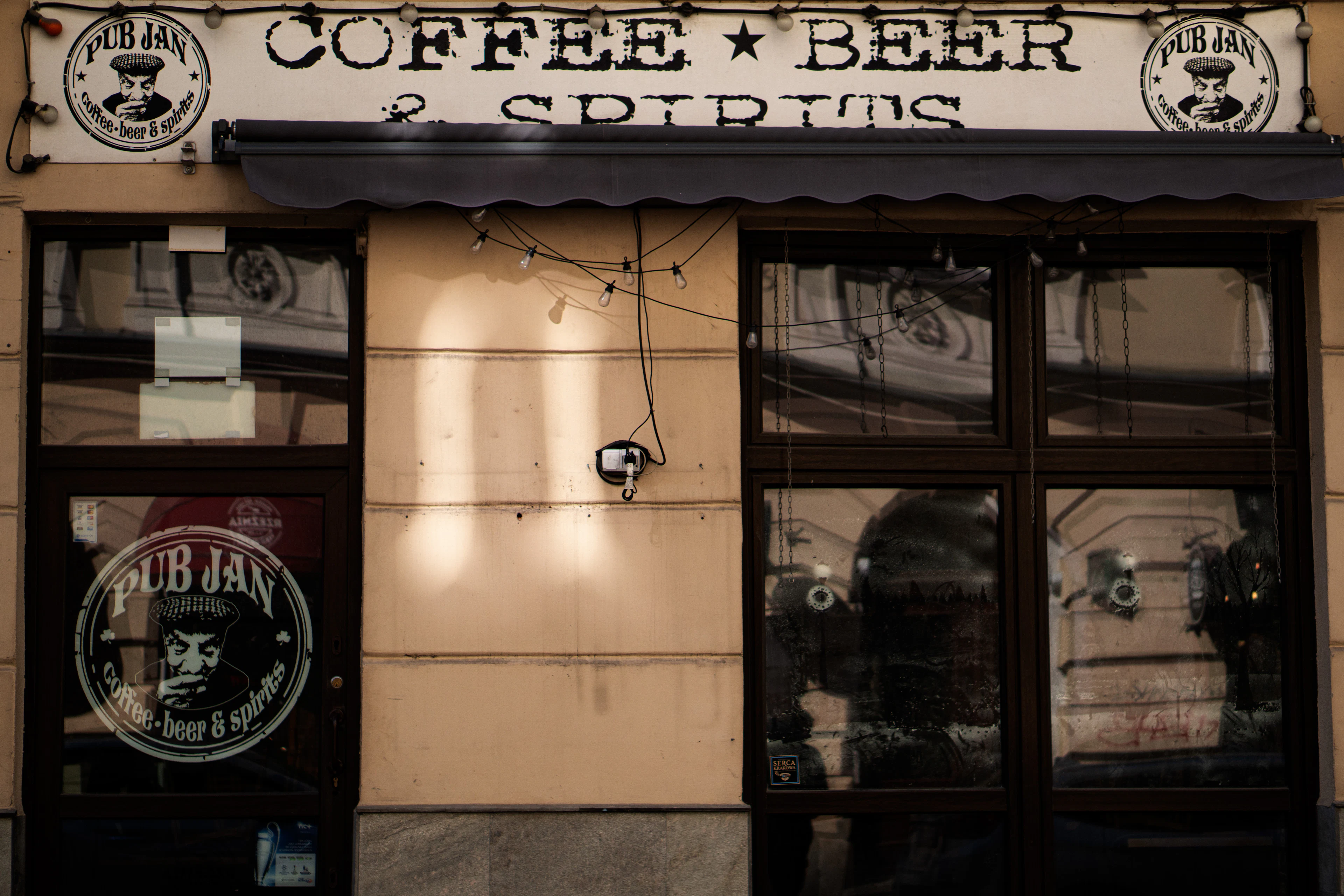 Wejście do małej kawiarni i baru z szyldem Coffee Beer Spirits
