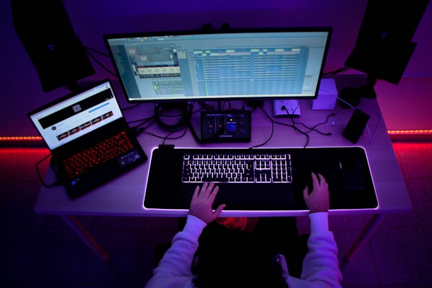 A focused professional working late at a sleek dark-themed office desk with glowing blue and white data charts on multiple screens.