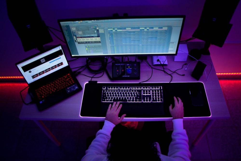 a person sitting at a desk with a computer and a keyboard