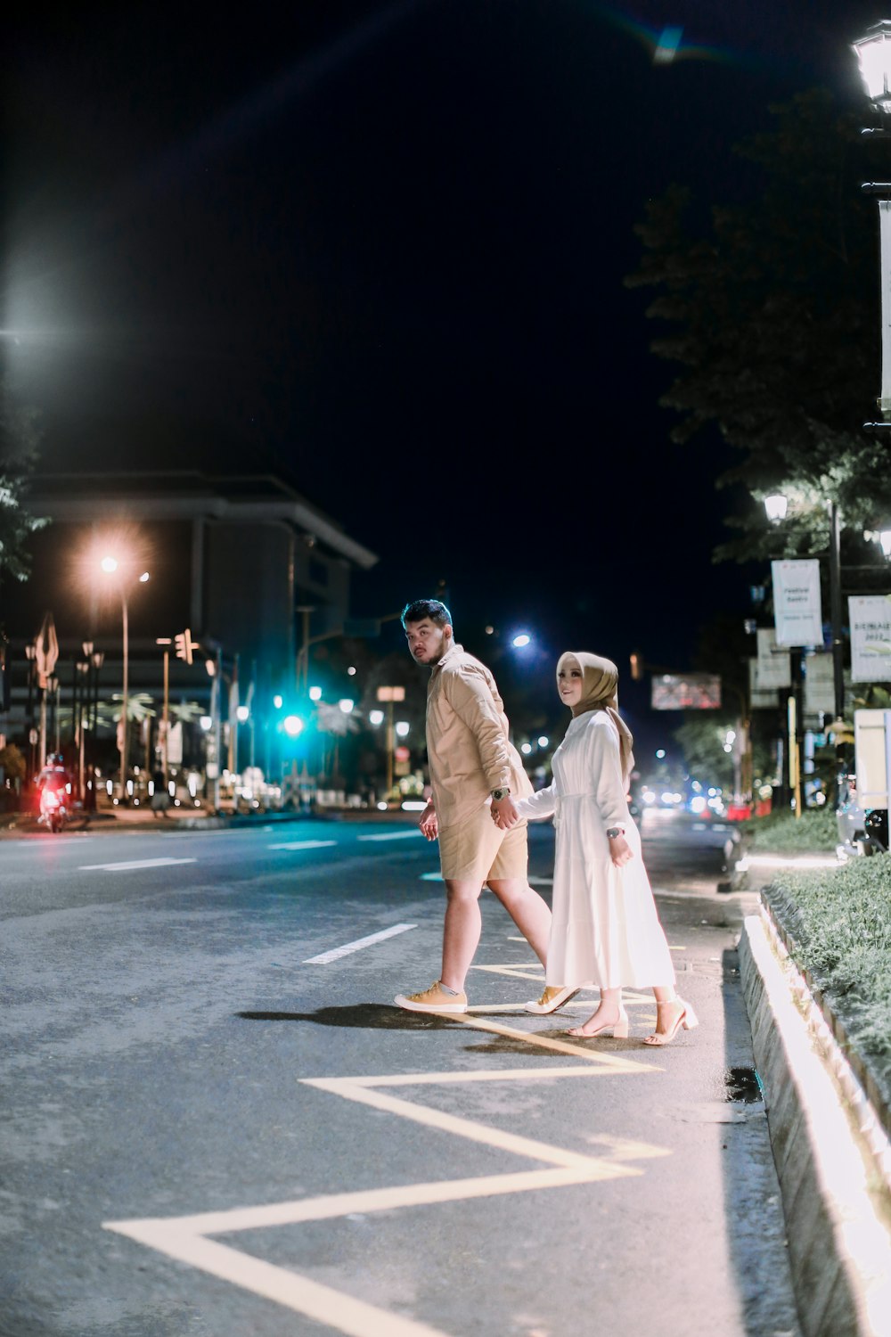 a man and woman walking down a street at night